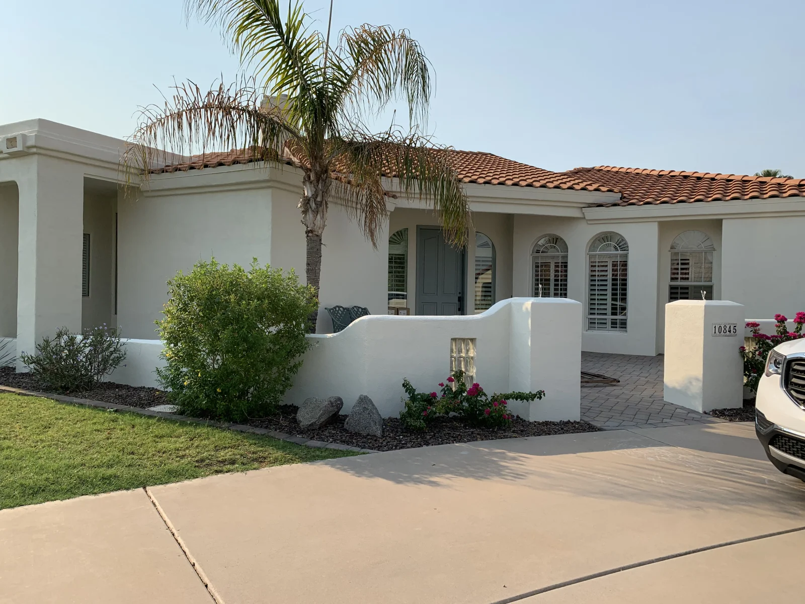 After: Single-story Spanish-style home with freshly painted white stucco walls after exterior painting