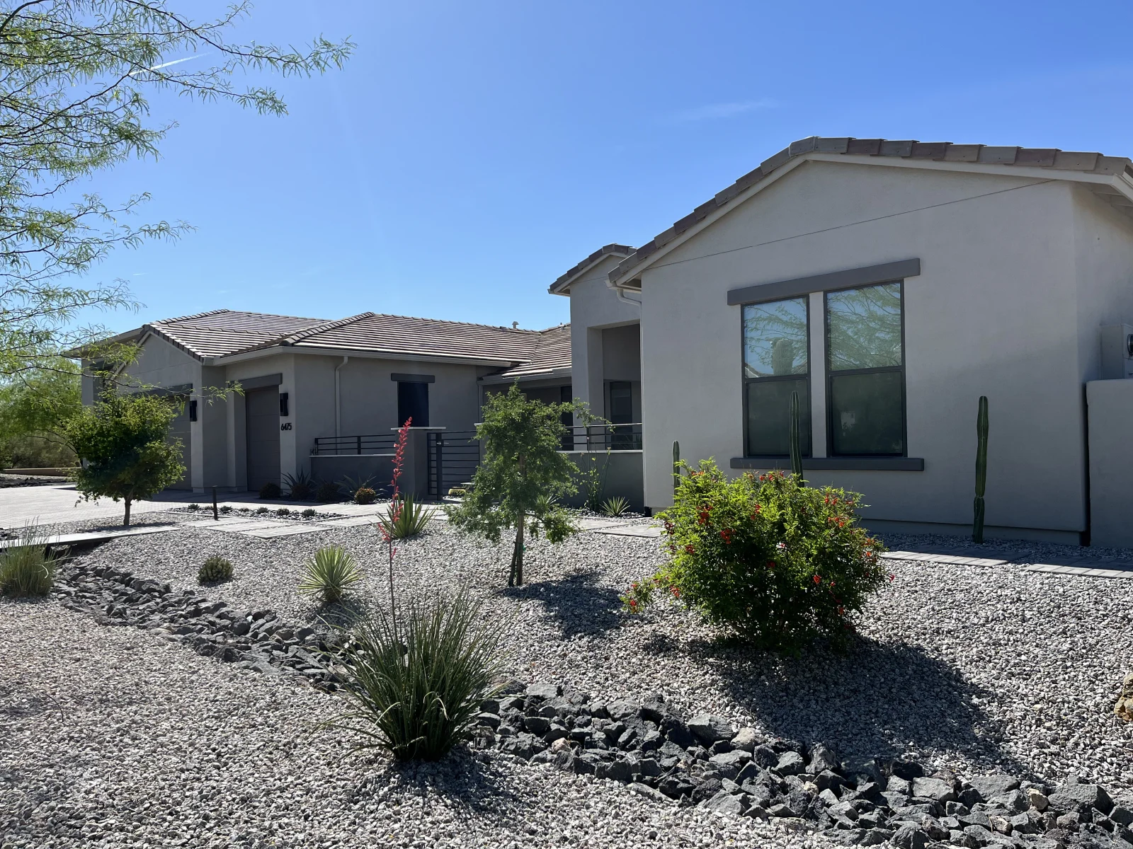 Light gray stucco home with dark gray window trim and tile roof after exterior painting