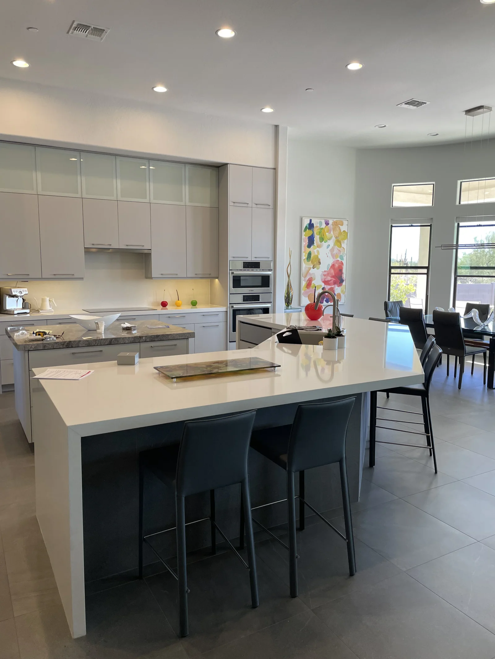Modern kitchen with gray flat-panel cabinets, frosted glass uppers, and white waterfall island after cabinet painting
