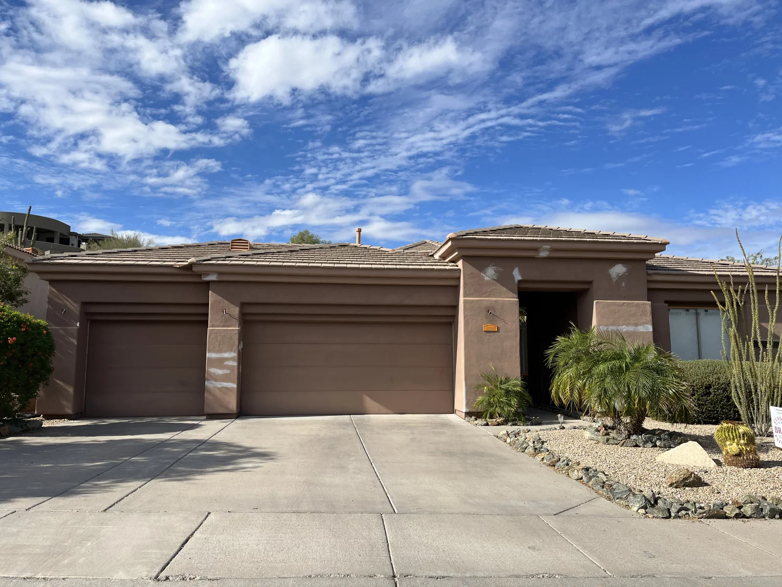 Before: Single-story stucco home showing patched stucco areas before repainting
